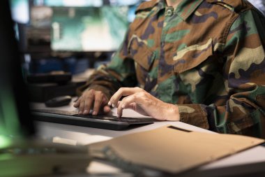 Air force combat control officer typing on keyboard, performing tactical level surveillance, close up. Military specialist using radar to search for potential assault zones, inputting coordinates
