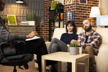 Karı koca terapi seansından sonra rahatça gülümsüyor. Terapist ofisindeki beyaz çift kameraya bakıyor, yapıcı danışmanlık tartışmasının ardından pozitif ve tatmin oluyorlar..