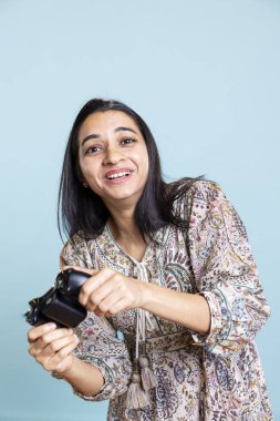 Stüdyoda joystick 'te video oyunu oynayan Hintli kız stüdyoda arka planda dururken zaferi kutluyor. Oyun oynamayı seven heyecanlı bir genç..