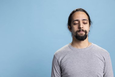 Huzurlu ve rahat bir genç, meditasyon yaparken gözleri kapalı, sağlığını ve derin rahatlığını göstererek hayattaki büyük dengeyi sağlıyor. Erkek kişi meditasyon yapıyor ve dinleniyor..