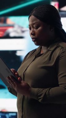 Vertical video Woman using tablet, receiving personalized video recommendations delivered instantly. African american user using device, enjoying digital era enabling unlimited streaming opportunities