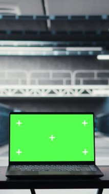 Vertical video Green screen laptop in high tech data center facility with multiple rows of fully operational server racks. Mockup notebook used to oversee server hub built for digital storage systems