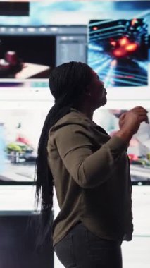 Vertical video Woman in front of digital videowall amazed by streaming videos and social media clips. User feeling mesmerized after accessing thousands of entertainment options through multimedia