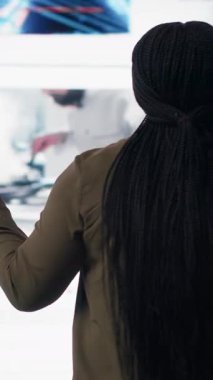 Vertical video User enjoying watching unlimited video streaming service content library on dynamic media wall filled with viral clips. Woman living entertainment focused digital age lifestyle, camera