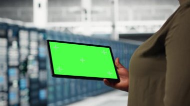 Hatasız süper bilgisayar ağlarını sağlamak için yeşil ekran tableti kullanan veri merkezinde bilişim uzmanı. Afrikalı Amerikalı kadın sunucu merkezi ekipman parçalarını takip etmek için model aygıtı kullanıyor, kamera B