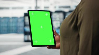 Server room admin uses isolated screen tablet to increase supercomputers workload capacity. Data center worker configures gear with chroma key device notebook, improving processing speed, camera B