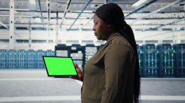 Server room admin uses isolated screen tablet to increase supercomputers workload capacity. Data center worker configures gear with chroma key device notebook, improving processing speed, camera A