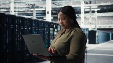 Yeni sunucu mimarisinin konuşlandırılmasını koordine etmek için dizüstü bilgisayar kullanan veri merkezi işyeri programcısı. Sunucu odası çalışanı, siber güvenlik çerçevesini açmak için dizüstü bilgisayar kullanıyor, verileri koruyor, kamera A