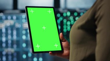 Sistem istikrarını kontrol etmek için veri merkezinde yeşil ekran tableti kullanan yazılım geliştiricisi. Afro-Amerikalı kadın sunucu çiftliğini denetlemek için krom anahtar kullanıyor. Kamera B.