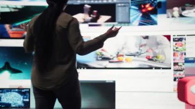 Viewer looking at video wall, watching content, enjoying digital age lifestyle. African american woman enjoying social media technology bridging people worldwide, camera A