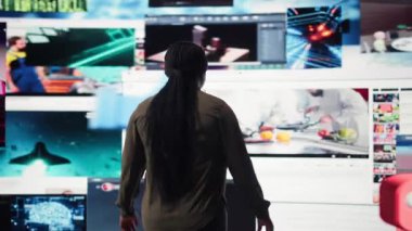 Çevrimiçi videoların dijital platformlarla beslenmesine hayran olan bir kadın. Evrensel kanalların viral klipler listesiyle gösterge panelini, kamera A 'yı gösteren sanal video duvarı tarafından büyülenen kişi