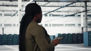 Manager in data center using tablet to coordinate deployment of new server architecture. Server farm IT expert using device to do rollout of cybersecurity framework, protecting data, camera B