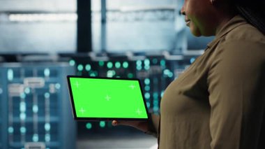 Data center software developer uses green screen tablet to minimize infrastructure downtime. IT specialist in server hub enhancing data protection safeguards using mockup device, camera B