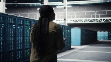 Data center technician using machine learning on tablet to optimize operations. IT specialist using device in server room with specialized gear accelerating complex AI calculations, camera A