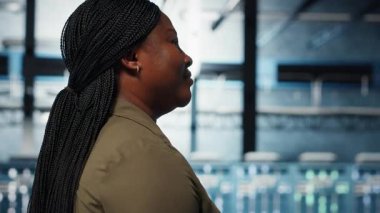 Technician in data center overseeing large scale IT gear to maintain seamless operations. IT professional walking in server hub, doing network management for increased uptime, camera B