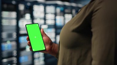 Employee using app on mockup mobile phone to check server hub energy consumption. Data center engineer using application on isolated screen smartphone to check power usage levels, camera B