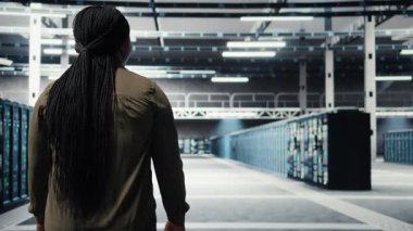 Admin in data center workplace overseeing large scale IT electronics to maintain seamless operations. Woman walking in high tech server room, doing network management for increased uptime, camera A