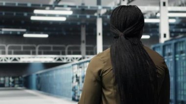 Admin in data center workplace overseeing large scale IT electronics to maintain seamless operations. Woman walking in high tech server room, doing network management for increased uptime, camera B