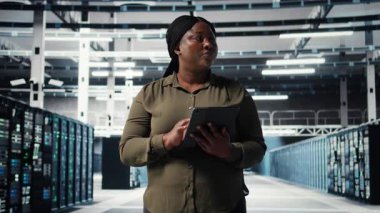 Technician using tablet in data center, integrating new technologies and systems. Employee using device to oversee server hub, ensuring compliance with industry standards, camera A