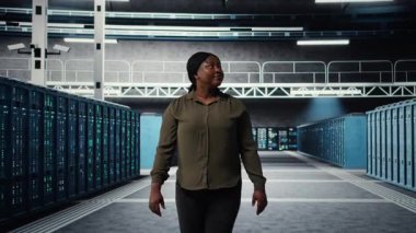 Portrait of smiling admin walking in data center, overseeing large scale IT infrastructure to maintain seamless operations. Happy server farm employee pleased by increased uptime, camera A