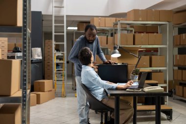 Two staff members manage orders and oversee cargo operations from local business, working in a compact industrial depot. People utilizing modern technology for e commerce service.