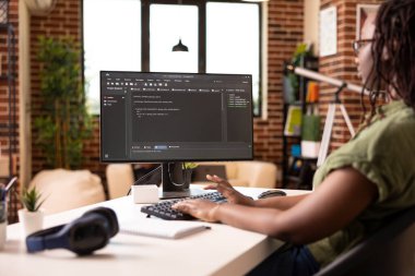 Siyahi kadın müteahhit, teknolojik girişimler için yazma ve sorun çözme kodları yazıyor. Kadın girişimci tuğla duvar dairesindeki masaüstü bilgisayarını kullanarak uygulama geliştirmeye odaklandı.