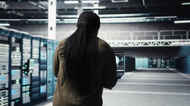 Engineer doing data center automation using AI software tools on laptop. Server room IT specialist implements artificial intelligence driven predictive maintenance systems using notebook, camera A