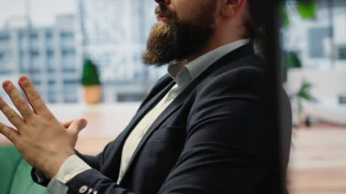 CEO leans back in his office chair engaging in a guided meditation session with white noise, using a meditation app. Commitment to mindfulness for career success and mental clarity. Camera B.