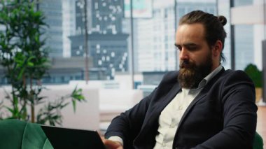 CEO modern ofisinde farkındalık üzerine pratik yapıyor ve mobil bir uygulama aracılığıyla meditasyon müziği dinliyor. Sakin duruş ve kapalı gözler, kurumsal baskılar arasında bir barış anını yansıtır. Kamera B.