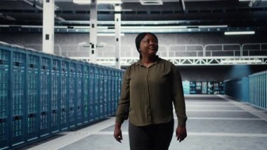 Engineer walking in data center, checking hardware for system stability. Employee overseeing server farm rigs, configuring infrastructure to optimize performance, camera A