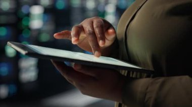 Close up of technician working in data center using tablet to optimize network infrastructure. IT expert in server farm diagnosing and resolving hardware malfunctions using device