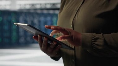 Sistem istikrarını kontrol etmek için veri merkezindeki yeşil ekran dizüstü bilgisayarı kullanan bir mühendis. Sunucu çiftliğini denetlemek ve altyapı, kamera B 'yi yapılandırmak için maket defteri kullanan işçiler