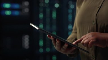 Veri merkezinde çalışan yöneticinin ağ ana bilgisayarlarını optimize etmek için tablet kullanarak yakın çekim görüntüsü. Sunucu çiftliğindeki IT çalışanı aygıt kullanarak donanım arızalarını tespit edip çözüyor