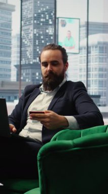 Vertical Video Responsible businessman verifies payment details on his laptop and managing corporate expenses, demonstrating financial planning and management in a modern office. Successful CEO