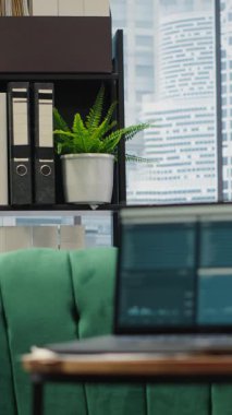 Vertical Video Modern high end empty office space with a laptop running infographics and data reports, professional workspace with screen showcasing the trends for the financial district.