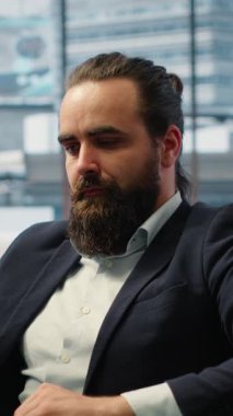 Vertical Video Male leader in a smart office thinking about ways to increase business profit, showcasing productivity while he manages company investments. Chief executive officer in office. Camera A.