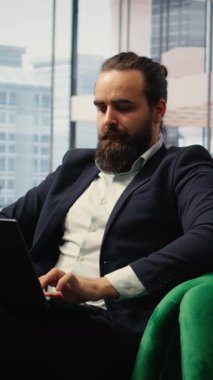 Dikey Video CEO 'su modern ofisinde bir mobil uygulama üzerinden meditasyon müziği dinleyerek farkındalık pratiği yapıyor. Sakin duruş ve kapalı gözler, kurumsal baskılar arasında bir barış anını yansıtır.