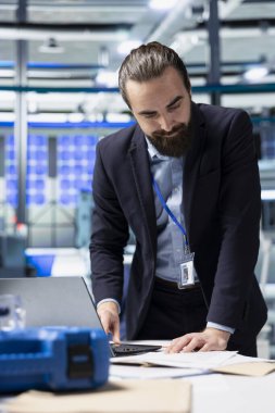 Üretim analisti, yüksek teknolojili endüstriyel bir ortamda, teknolojik hassasiyet ve sürdürülebilir enerji geliştirme üzerine odaklanarak, güneş paneli üretim iş akışını gözden geçiriyor..