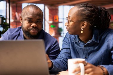 Siyah çift evlerinde uzak görevlerde birlikte oturup pazarlama stratejilerini tartışıyor ve serbest projelerini planlıyorlar. İnsanlar evlerinde araştırma yapıyorlar..