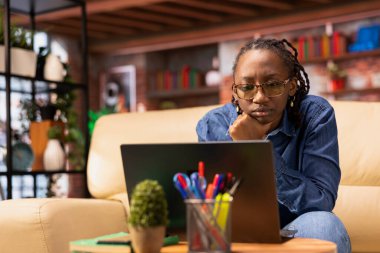 Ev işlerinde dizüstü bilgisayar kullanan bağımsız bir kadın, araştırma yapıyor ve program esnekliğinin faydalarından keyif alıyor. Serbest çalışmanın modern yaşam tarzını benimsemek.