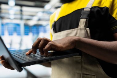 Afrikalı Amerikalı mühendis, endüstriyel parametreleri güneş enerjisi üretimi için ayarlıyor, yüksek teknoloji üretim tesisinde çalışıyor. Bilgisayar ve ince ayar üzerine teknik veriler analiz ediliyor.