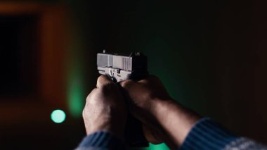 Atış galerisi müşterisi, kağıt hedefleri vurmak için tabanca kullanıyor. Kapalı alandaki atış poligonu tesisinde güvenlik ekipmanı takan birini yakından çek. Boğa avcılarını vur. Silah kullanmaktan zevk al.