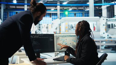 Fotovoltaik fabrikası programcısı yenilenebilir enerji jeneratörlerinin modellerini oluşturarak yöneticiye ilerleme sunuyor. Güneş panelleri bitki geliştirici güvenli güneş hücreleri inşa eder. Yönetici, kamera A ile konuşur.