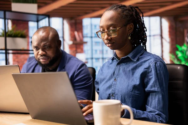 Modern masalarında çalışan Afrikalı Amerikalılar serbest bir proje üzerinde çalışıyorlar, verimlilik ve stratejik planlama üzerine odaklanıyorlar. Genç adam ve kadın ayrı günlük görevlerini yapıyorlar..
