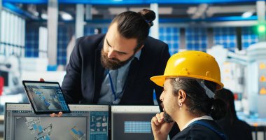 Fotovoltaik fabrikası mühendisi CAD yazılımında çalışıyor, müdürle beyin fırtınası yapıyor. Güneş panelleri üretim fabrikası teknisyeni montaj hatları tasarlıyor, danışman bilgilendirme, kamera B