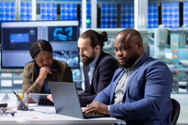 Investor in industrial plant using laptop to review manufacturing expansion documents. African american businessman looking at data on notebook to evaluate investment strategy