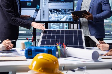 Factory researching team looking at new photovoltaics materials, close up. Businessmen in solar panel manufacturing plant discussing ways to use newly developed green energy systems prototypes