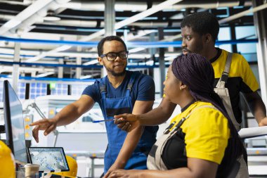 African american team of technicians doing quality control on pc, troubleshooting and fixing technical issues for solar panel production at high tech factory. Coworkers inspecting system.