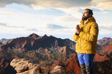 Keyifli bir doğa aşığı dağ sırasının tepesinde meditasyon yapıyor, meditasyon yapıyor ve rahatlık ve zihinsel berraklık için derin nefesler alıyor. Huzurlu zen yürüyüşçüsü tırmanmayı sever.