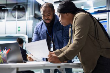 Yüksek teknolojili bir güneş paneli tesisinde veri ve kontrol listelerini inceleyen bir grup profesyonel danışman, üretim sürecinin sürdürülebilir enerji ve yenilik standartlarını karşılamasını sağlıyorlar.